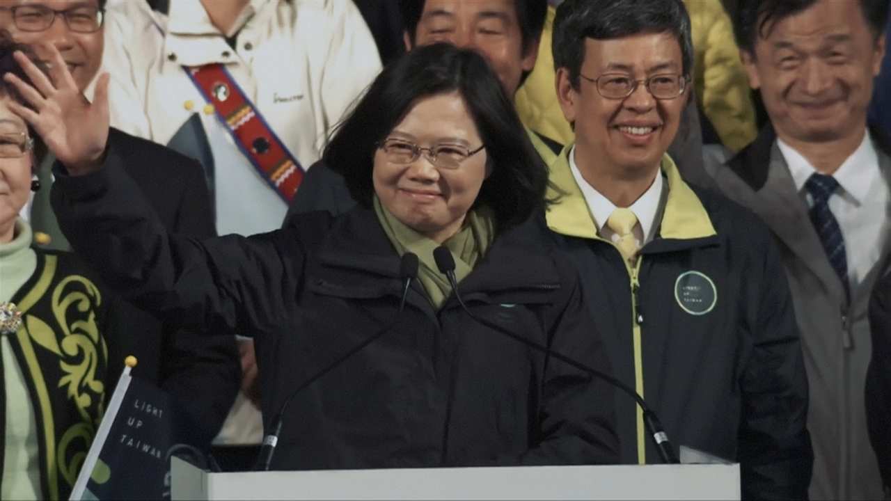 a woman with glasses waving at a podium